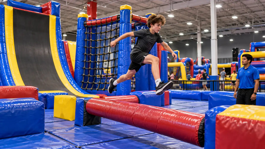 A large inflatable ninja warrior course at an indoor family entertainment center, with a warped wall, cargo net and balance elements, and a teenager mid-run